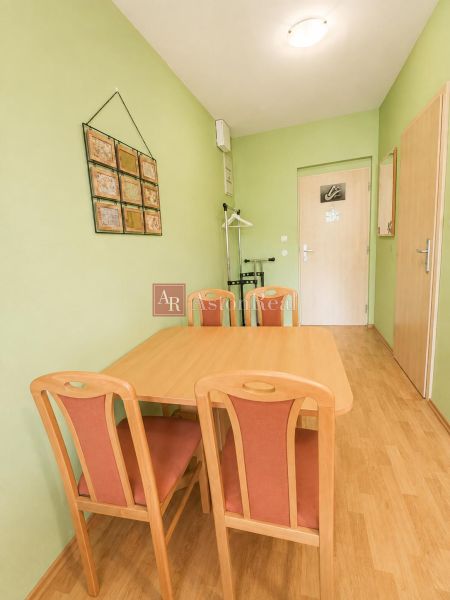 A dining room with a wooden table and chairs, and a floor with a wooden decor.