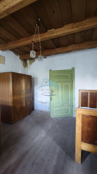 A room in a family house with a wooden ceiling, green doors, and furniture.