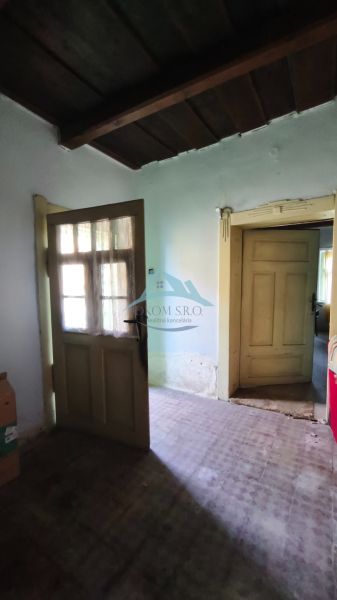 Interior of a family house with a wooden ceiling, doors, and an older floor.