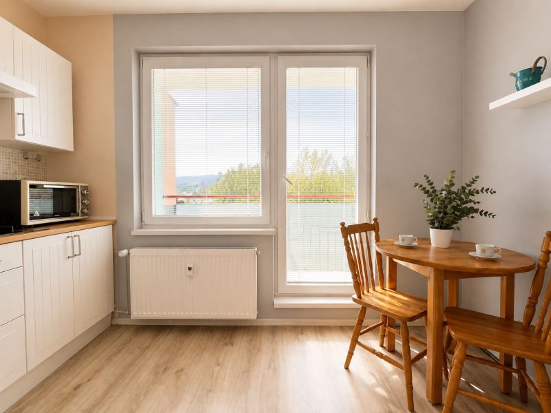 A one-room apartment with a kitchenette, dining table, and floor with a wood decor.