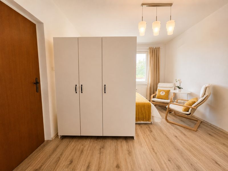 Interior of a 1-room apartment with a white wardrobe and a wooden decor floor.