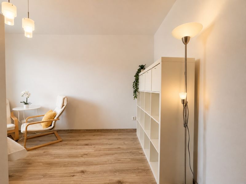 A room with a wooden decor floor, a white shelf, and a comfortable armchair.