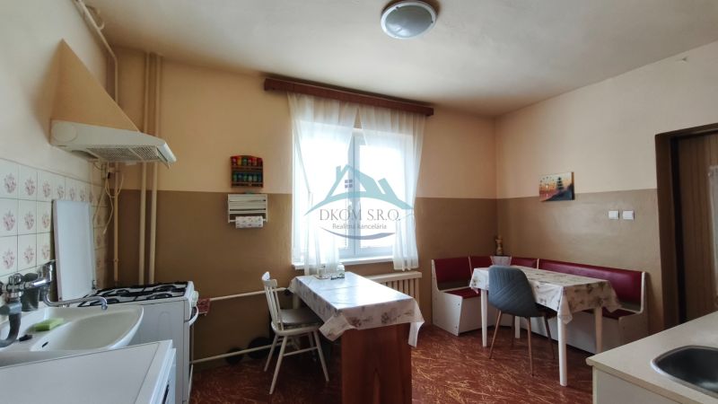 A kitchen in a family house with a dining area and a floor with a wooden decor.
