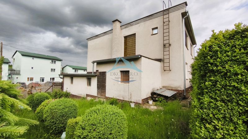 A family house in Nenince with a lawn and shrubs, under a cloudy sky.