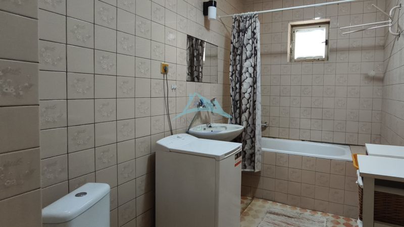 Bathroom with a bathtub, sink, and washing machine in a family house.