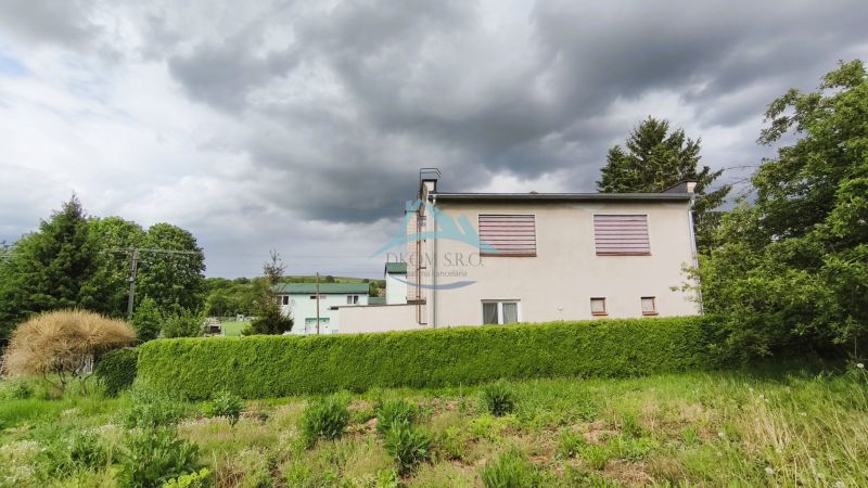 A family house in Nenince surrounded by dense greenery and trees under a cloudy sky.