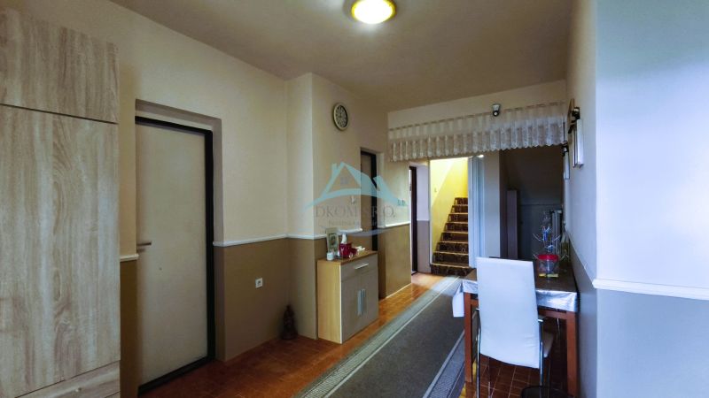 A hallway in a family house with a carpeted staircase, a table, and a floor with a wooden decor.