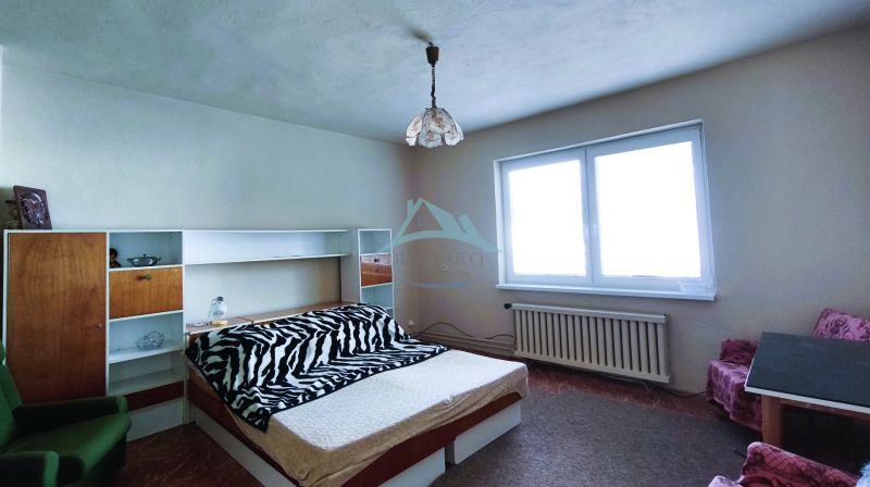 Bedroom in a family house with a bed, shelves, and a large window.