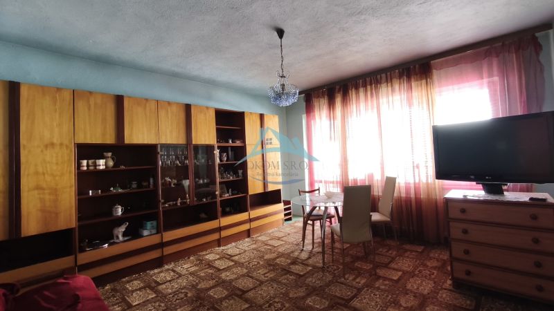 Living room in a family house with a showcase, dining table, and television.
