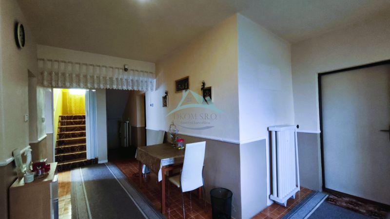 Dining area with white chairs and stairs in a family house.