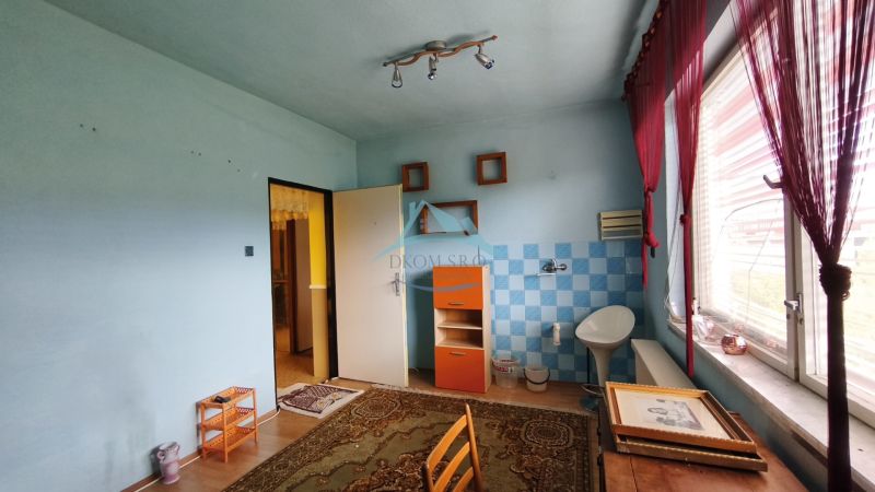 A room in a family house with tiles, a wooden-patterned floor, and a large window.