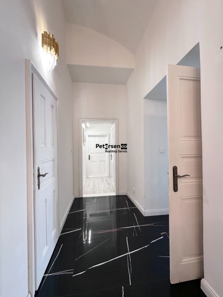 A hallway in a 3-room apartment with glossy tiles and stylish lighting.