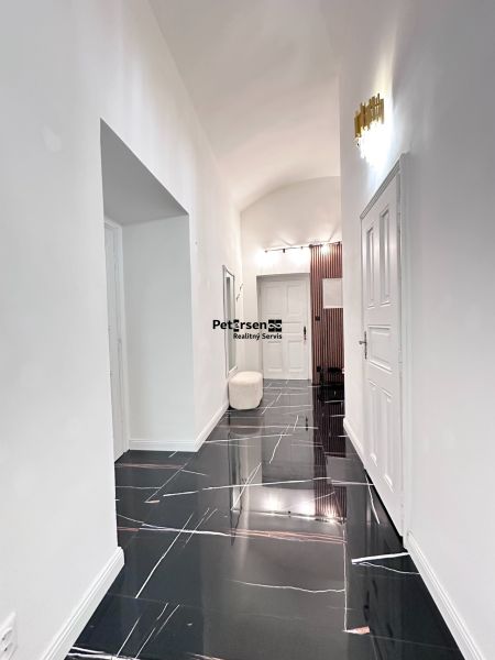A hallway in a 3-room apartment with an elegant black floor and lighting.