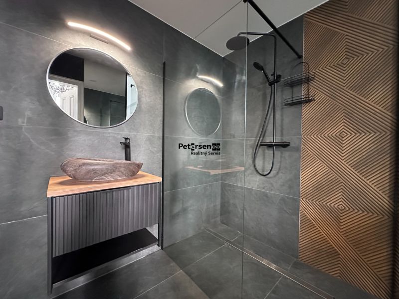 A bathroom in a 3-room apartment with a round mirror and a decorative wall.