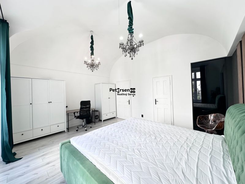 A bedroom with chandeliers and a desk in a three-room apartment with white wardrobes.