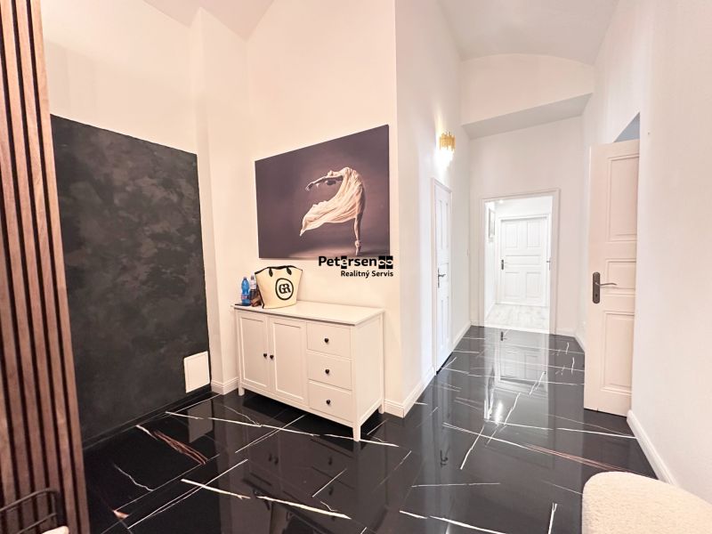 A hallway in a 3-room apartment with a dark floor and white furniture.