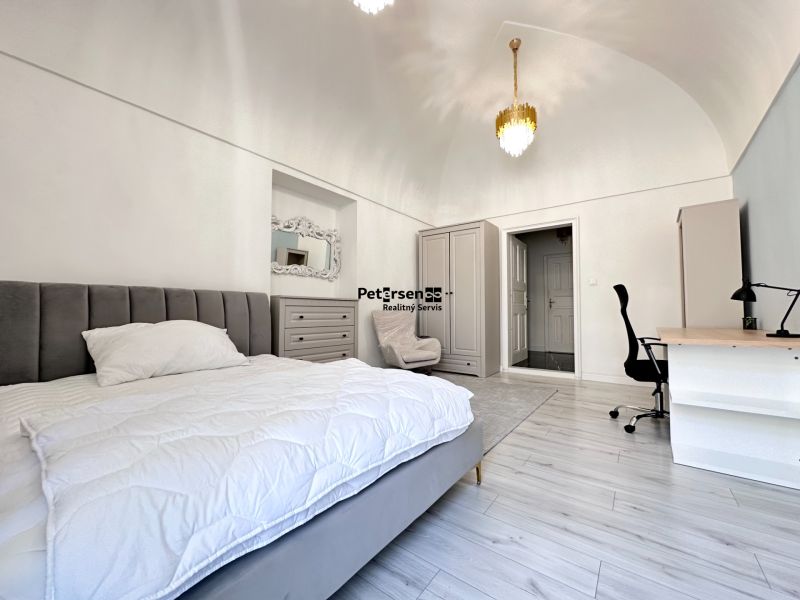 A bedroom in a 3-room apartment with wood-patterned flooring and stylish lighting.