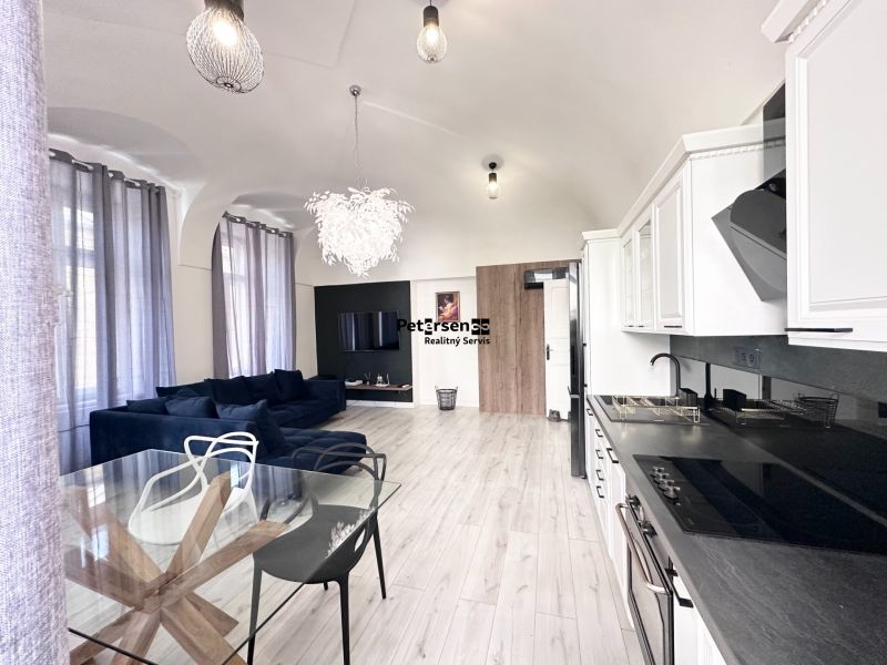 Living room with a corner sofa and kitchen in a 3-room apartment with a wooden decor floor.