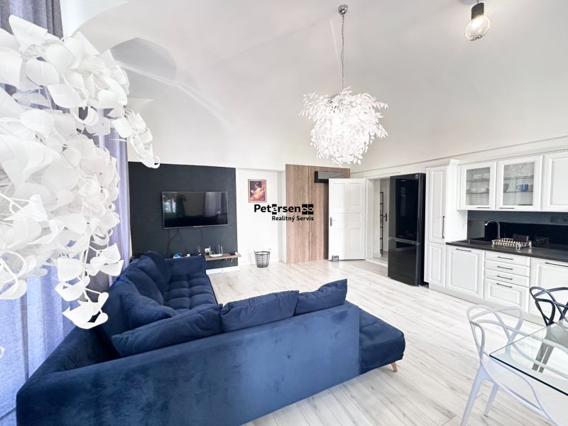 Interior of a 3-room apartment with a dark sofa, wooden decor flooring, and a stylish chandelier.