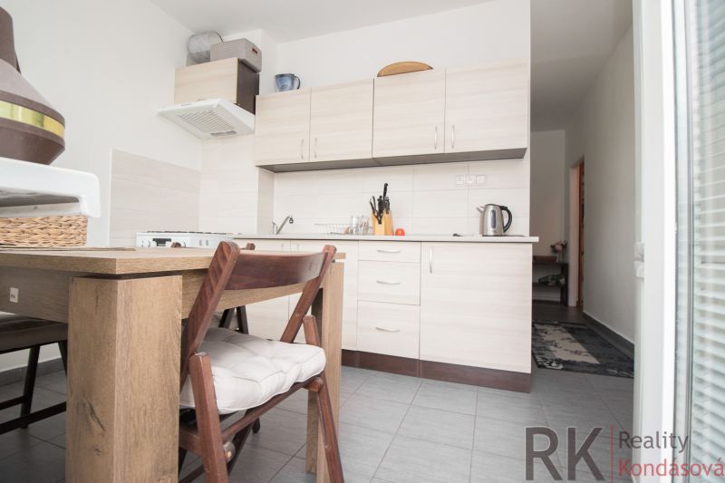 A kitchen in a 3-room apartment with a wooden table, light cabinets, and appliances.
