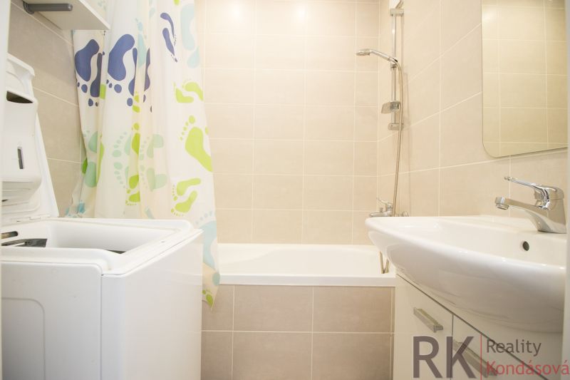 Bathroom with a bathtub, washing machine, and curtain in a 3-room apartment.