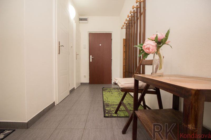 Entrance hall with decoration and hooks in a 3-room apartment, gray tiles on the floor.
