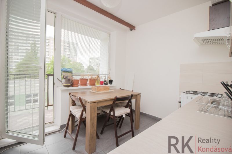 The kitchen in a 3-room apartment with a wooden table, large windows, and a balcony.