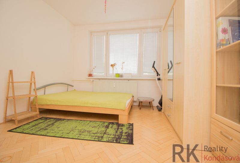 A bedroom with light furniture, a bed, and a wooden decor floor in a 3-room apartment.