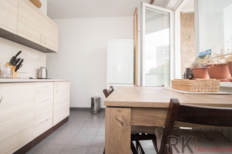 A kitchen in a 3-room apartment with a wooden decor, a table, and a view outside.