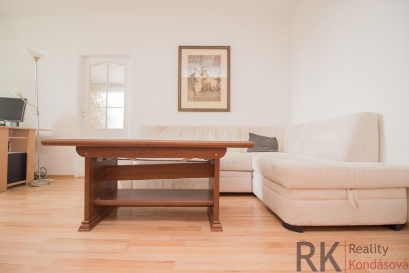 Living room with a corner sofa, table, and floor with wood decor in a 3-room apartment.