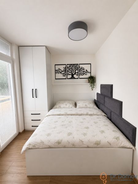 A bedroom in a studio apartment with wall decoration and a wooden decor floor.