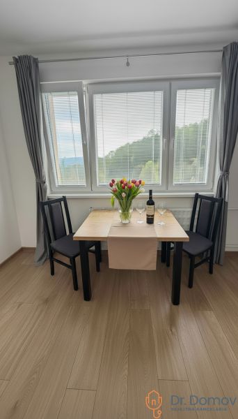 Dining area with flowers on the table, wooden decor flooring in a studio apartment.