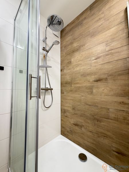 Shower corner with a floor with a wooden decor in a studio apartment.
