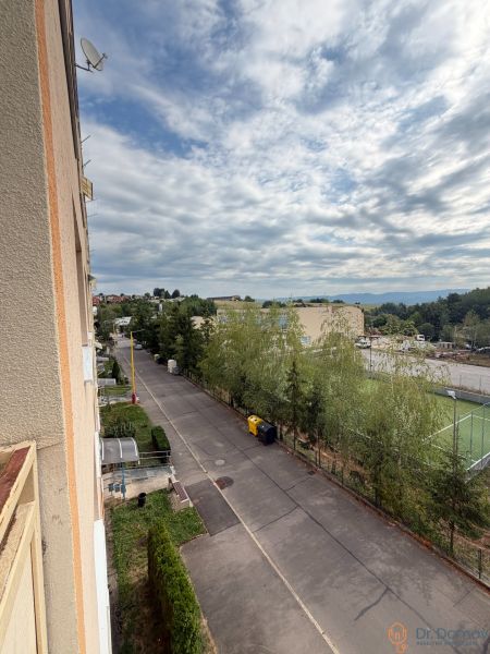 View from a 1-room apartment on Školská Street in Kanianka with a playground and sky.