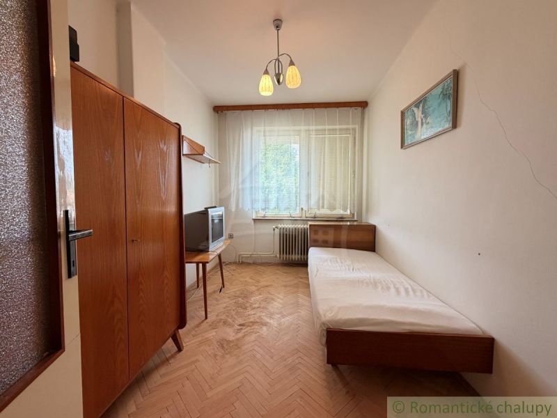 A simple room in a family house with a bed and a wooden decor floor.