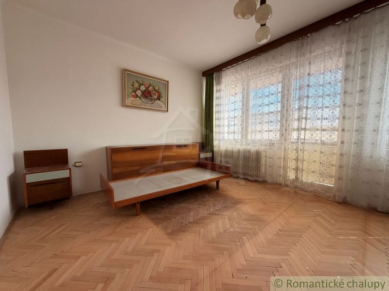 Interior of a family house with a wooden decor floor, retro furniture, and large windows.