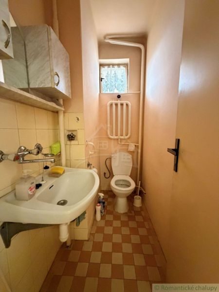A bathroom in a family house with a sink and a toilet, beige tiles and flooring.
