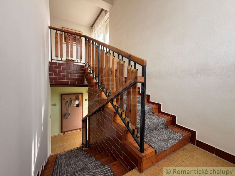 Staircase in a family house, wooden railing, carpet on the stairs, brick cladding.