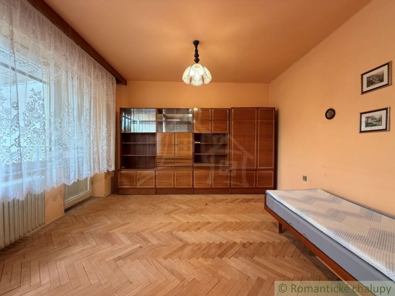 A room with a wooden floor decor, a wardrobe, and a bed in a family house.