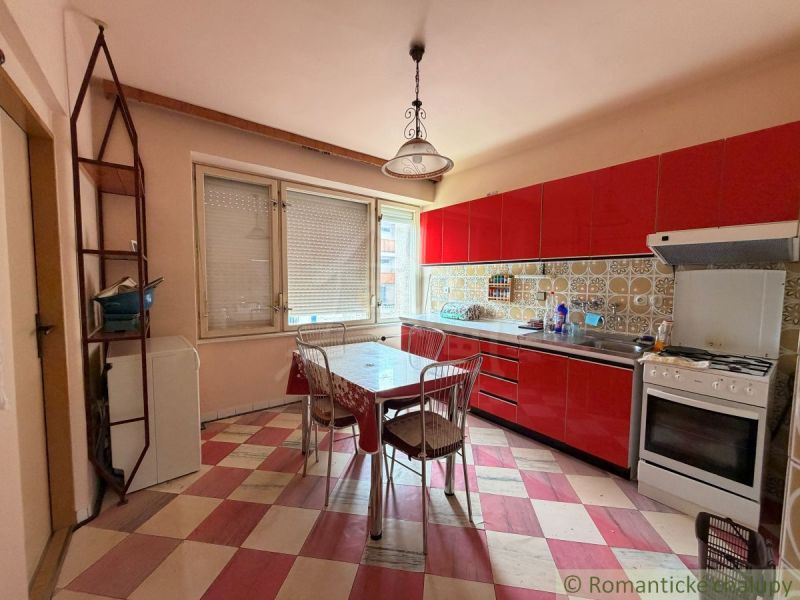 A kitchen in a family house with red cabinets and a checkered floor.