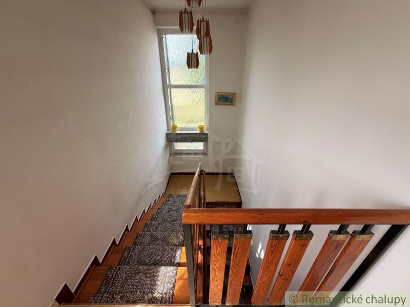 A staircase with a wooden railing and a window in a family house, flooring with a wooden decor.