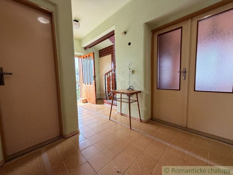 The hallway of a family house with simple furniture and light-colored doors.