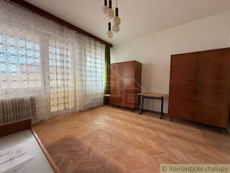 A room with a wooden floor decor, retro furniture, and hanging curtains in a family house.