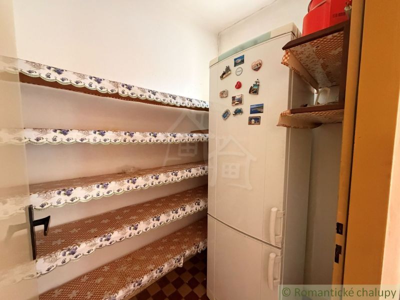 Pantry in a family house with shelves and a refrigerator decorated with magnets.