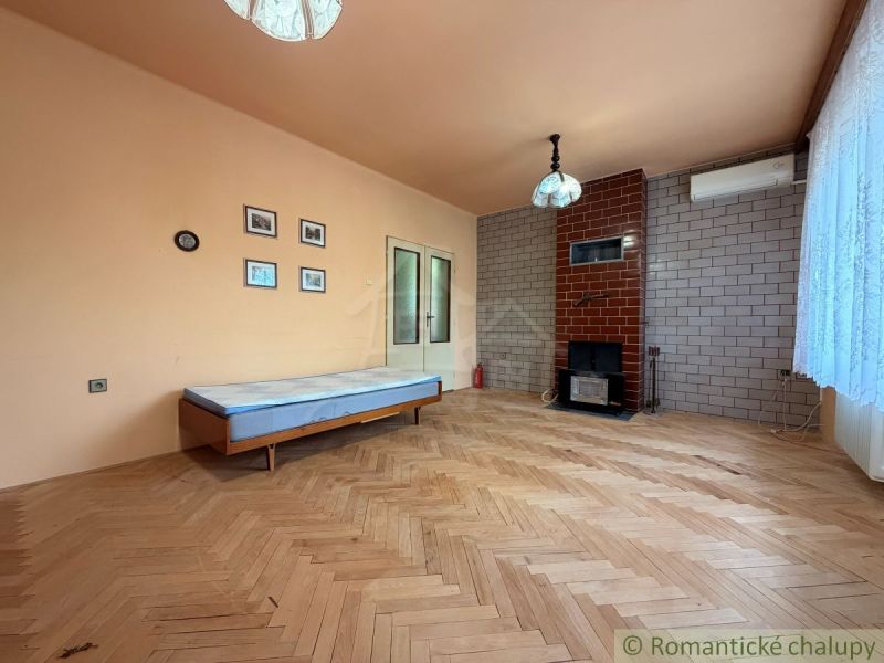Living room with a fireplace, wood-patterned flooring, and a sofa bed in a family house.