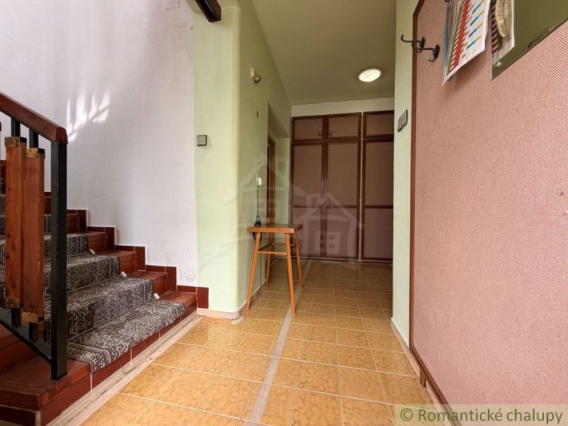 A hallway with wooden stairs and light walls in a family house.