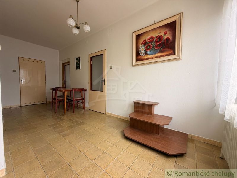 Dining room in a family house with a painting, floor, table, and chairs.