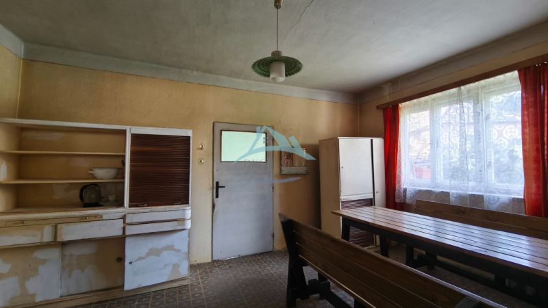 A kitchen in a family house with wooden furniture, a large window, and older equipment.