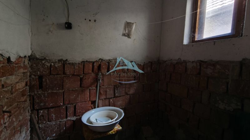 Incomplete bathroom in a family house with exposed bricks and a sink.