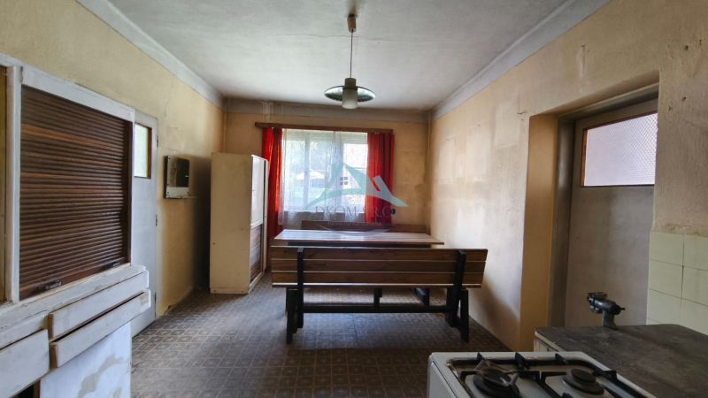 A kitchen in a family house with a dining table, a stove, and red curtains.